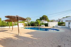 a patio with an umbrella and a swimming pool at Moraira Sweet Home with AC in Teulada