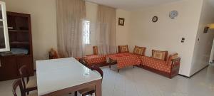 Una sala de estar con sofás y sillas y una mesa. en Villa lumineuse, double jardin, en Sidi Bouzid