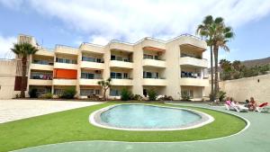 a large apartment building with a swimming pool and palm trees at Costamar Infinite Sea Views by Deihu Experiences in Los Cristianos