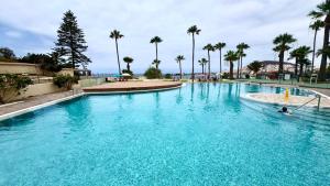 a large pool with blue water and palm trees at Costamar Infinite Sea Views by Deihu Experiences in Los Cristianos