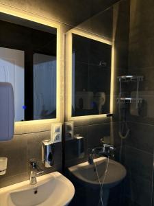 a bathroom with two sinks and two mirrors at Sataplia Inn in Tsqaltubo +50 photos