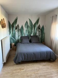 a bedroom with a bed with a large mural of leaves at Villa 170m2 avec piscine , sauna , jacuzzi , terrain de petanque in Nompatelize