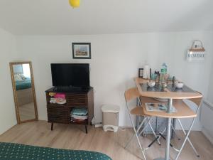 a living room with a television and a table with a desk at L'Escapade in Gonneville-la-Mallet