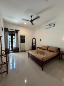 a bedroom with a bed and a ceiling fan at Sun & Moon Hostel in Mirissa