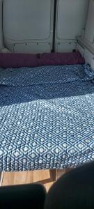 a bed with a blue and white comforter in a room at Autocaravana Camper in Las Palmas de Gran Canaria