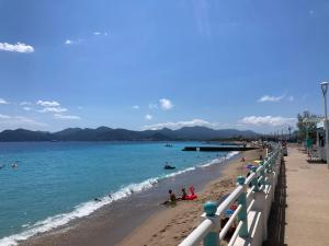 a beach with people sitting on the sand and the water at Appartement maisonnette de vacances in Cannes