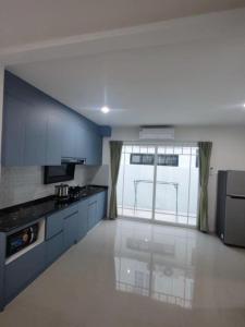 une grande cuisine avec des placards bleus et une grande fenêtre dans l'établissement Bristol park 233, à Ban Huai Yai 5 autres photos