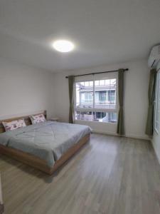 une chambre avec un lit et une grande fenêtre dans l'établissement Bristol park 233, à Ban Huai Yai