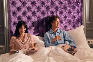 a man and a woman sitting in a bed at Aria Hotel Budapest by Library Hotel Collection in Budapest