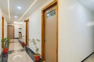 a hallway with potted plants in a building at Hotel O Happy Times Vishveshwar Park in Gomti Nagar