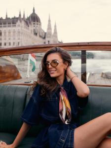 a woman sitting on a boat in front of the city at Aria Hotel Budapest by Library Hotel Collection in Budapest