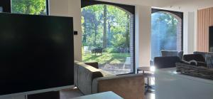 a living room with a flat screen tv and chairs at Guesthouse Les Buttes in Bruges