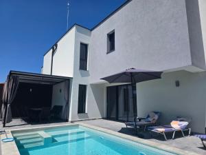 a swimming pool with chairs and an umbrella next to a house at Villa Cadaques in Lozenets