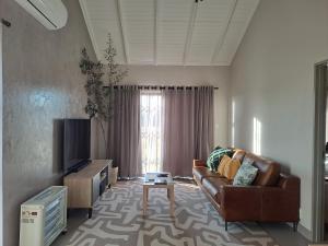 a living room with a couch and a television at Endon Cottage in Bloemfontein