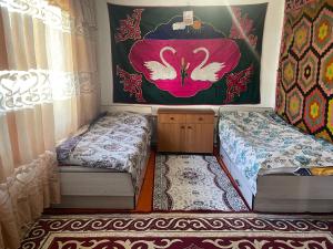 a room with two beds and a painting on the wall at Aina guesthouse in Kyzyloy
