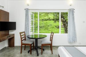 een kamer met een tafel, stoelen en een raam bij Royal Mist Villa- Homestay in Munnar +15 foto's