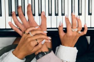 two hands with white nail polish playing a piano at Aria Hotel Budapest by Library Hotel Collection in Budapest