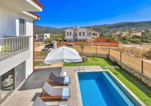 a swimming pool with chairs and an umbrella next to a house at Villa Serenity in Kas