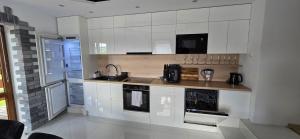 a kitchen with white cabinets and a sink at Apartament u Krupy z Prywatnym Jacuzzi i tarasem Widokowym in Murzasichle