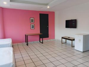 a room with a pink wall and a table and a tv at Unidades Privadas con AC-TV-WiFi y Estacionamiento en Centro de MTY in Monterrey