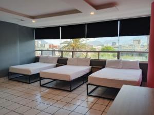 a room with two beds and a large window at Unidades Privadas con AC-TV-WiFi y Estacionamiento en Centro de MTY in Monterrey