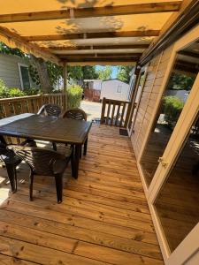 a patio with a table and chairs on a deck at Mobil-home - Valras Plage - Les Sables du Midi 4 étoiles in Sérignan
