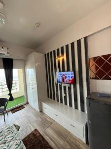 Una sala de estar con un televisor en la pared. en Lumora lofts, en Greater Noida