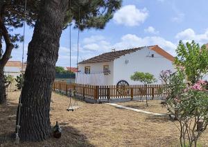 una casa con una valla y un árbol con columpios en Casa do Lagar, en Óbidos