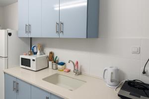 a white kitchen with a sink and a microwave at רימון יחידות אירוח Vacation units RIMON in Ashkelon