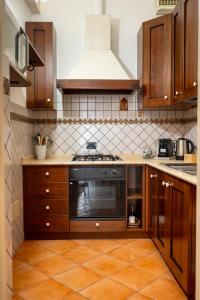 a kitchen with wooden cabinets and a stove top oven at Artista Apartment in Alcamo