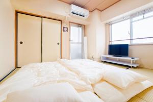 a large white bed in a room with a tv at Du Etowaaru in Nagoya