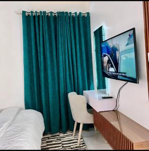 a bedroom with a green curtain and a television at Woodhaven apartment in Kado