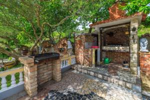 an outdoor kitchen in a brick house with a tree at Apartments Roby in Kampor