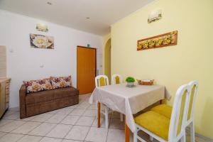 a dining room with a table and a couch at Apartments Roby in Kampor