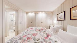 a white bedroom with a bed with a floral blanket at Uep Soel in Kampen +3 photos