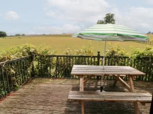 a picnic table with an umbrella on a boardwalk at Uplands in Compton