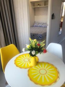 une table blanche avec un vase jaune et des fleurs sur elle dans l'établissement Milan Soria Luxury Coblanca XII, à Benidorm 35 autres photos