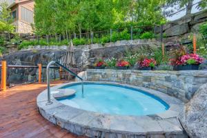 a hot tub in a landscaping with a stone wall at Tremblant Prestige - Equinoxe 140-1 in Mont-Tremblant