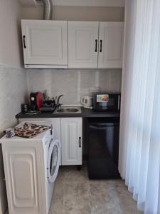 a kitchen with white cabinets and a washer at Marea Garden, Ravda - Studio with Pool by Flat Mаnager in Ravda