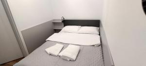 a small bed with white sheets and towels on it at Rabka Serenity in Rabka