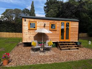 a tiny house with two chairs and an umbrella at Hut in the hall in Bedale