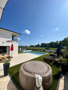 ein Hinterhof mit einem Pool und einer großen runden Feuerstelle in der Unterkunft Villa in Sainte-Eulalie