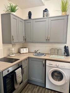Una cocina con gabinetes blancos y lavadora. en The Valley View Apartment, en Great Harwood