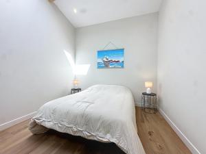 a white bedroom with a bed and two lamps at Maison à 2 min de la plage Saint Georges de Didonne in Saint-Georges-de-Didonne
