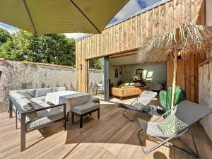 a patio with a couch and chairs and an umbrella at Maison à 2 min de la plage Saint Georges de Didonne in Saint-Georges-de-Didonne