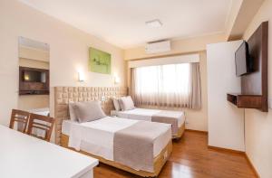 a hotel room with two beds and a television at Hotel Marbor in Mogi das Cruzes