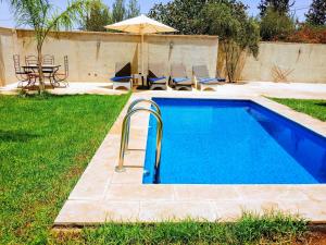 a swimming pool with an umbrella and a table and chairs at Riad Elbahi in Marrakech