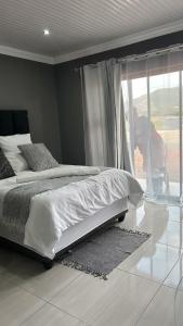 a bedroom with a bed and a person looking out the window at Okuhle Guesthouse Steelpoort in Steelpoort