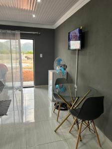a room with a glass table and a chair and a television at Okuhle Guesthouse Steelpoort in Steelpoort