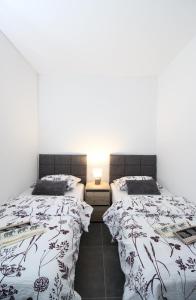 two beds in a room with white walls at Fly in Apartment in Čilipi